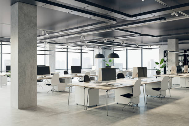 istock Comfortable workplaces in an open office interior with desks, computers, and a window. The design is sleek with a concrete floor and black ceiling. Business background. 3D Rendering 1498648335