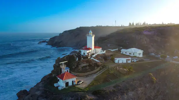 Aerial shot of the historic Cape St. Blaize lighthouse in Mossel bay, constructed in 1864 standing 14 meters tall during sunset with a view of the ocean.