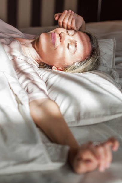 istock Happy middle aged woman sits on bed and stretching arms 1498649782