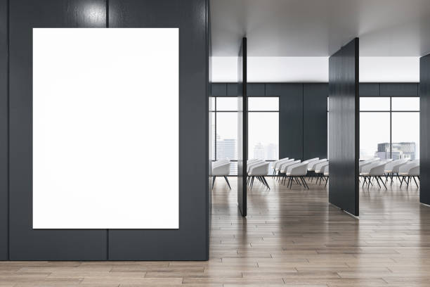 istock Front view on blank white poster with space for your logo or advertising text on black wall partition in stylish conference area with city view from big windows and chair rows. 3D rendering, mock up 1498649818