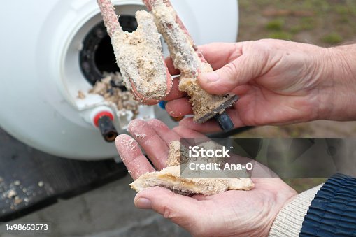istock Repair and maintenance of boilers. The plumber pulls the tubular electric heater out of the hole in the boiler. Lime deposits on stainless steel heating element and anode. 1498653573