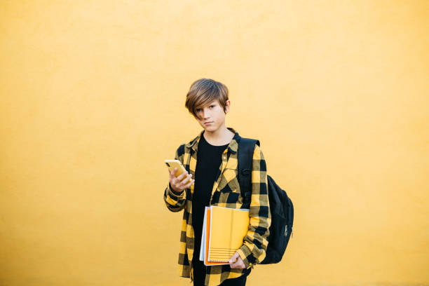 istock Teenager using an smartphone in front of a yellow background 1498655711