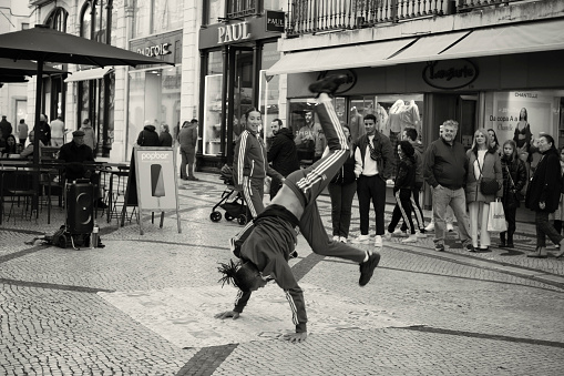 Lisbon, Portugal - January 15, 2023: A young man performs a hip-hop manouver at the Rua Augusta street in Lisbon downtown.
