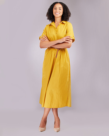 Beautiful young woman with brown hair in bun wearing yellow dress off shoulder and looking at camera, studio shot, beauty and fashion industry