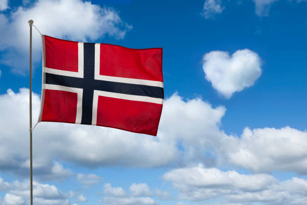 Norwegian flag against blue sky with cloud heart