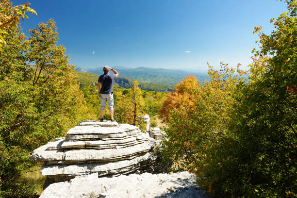 Male tourist exploring Stone forest, natural rock formation, created by multiple layers of stone, located near Monodendri village in Zagori region, Northern Greece. Male tourist exploring Stone forest, natural rock formation, created by multiple layers of stone, located near Monodendri village in Zagori region, Epirus, Northern Greece. zagori stock pictures, royalty-free photos & images