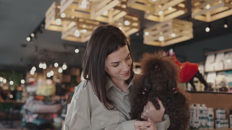 Young woman with poodle in pet shop