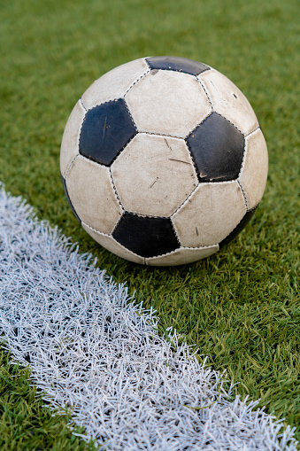 Old shabby classic soccer ball lies on the background of green grass