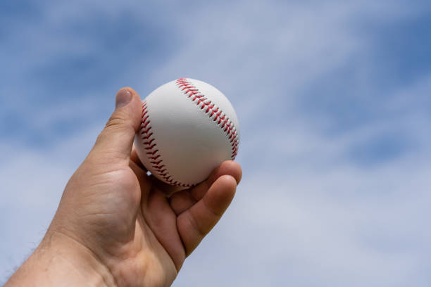 istock Man's hand holding a baseball ball at the stadium during the game 1498660349