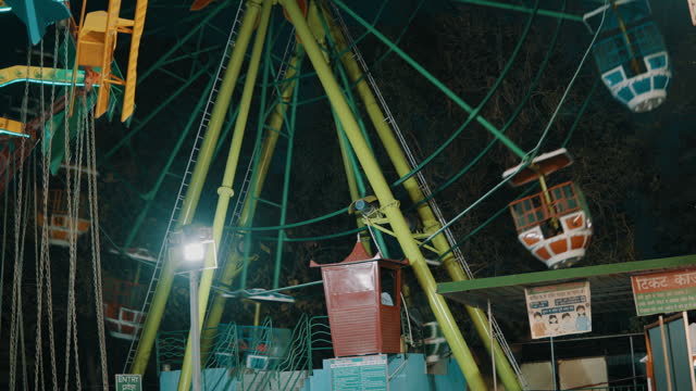 Ferris wheel and outdoor play equipment in illuminated amusement park