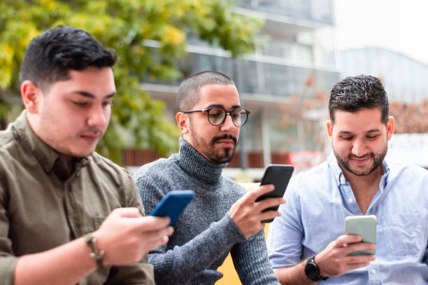 group of friends looking at their phones, sitting outside a bar. stock photo