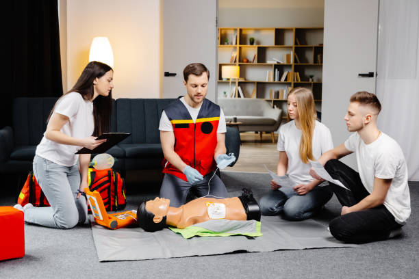 istock Young man instructor helping to make first aid heart compressions with dummy during the group training indoors 1498669555