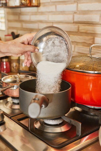 istock Chef pours sugar into pot on the gas stove 1498670174