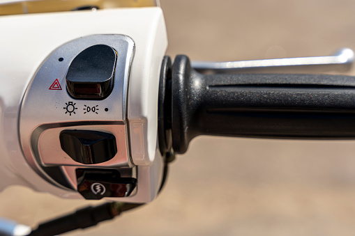 The throttle control knob and lighting fixtures on the handlebars of the motorcycle. the throttle handle on the handlebars of the scooter. Low beam and high beam lighting switch.