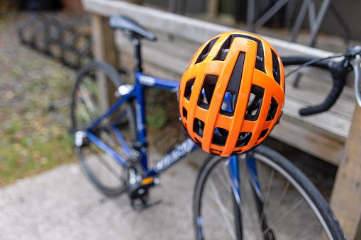 A close-up shot of a bike with a cycling helmet at a community cycle hub bike store in Hexham, England. The organisation is a mental health charity that connects people via cycling. The cycling hub encourages, fitness, education with a view to employment, friendship, mental well-being, mental health, volunteering, leadership skills, and community bike rides.