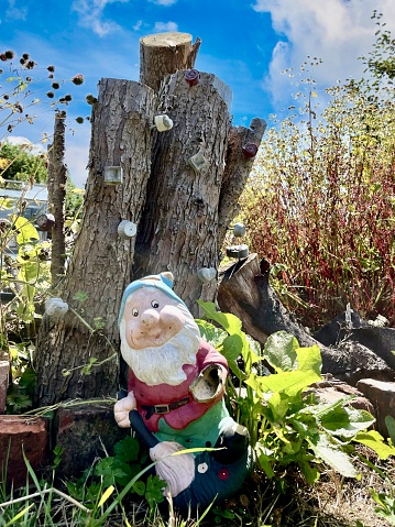 Gnome leaning against a tree stump .