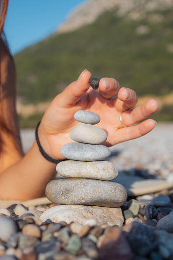 a girl on the beach balances stones