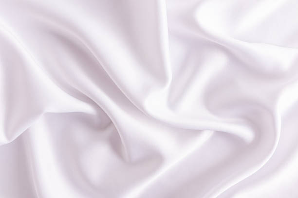 istock Delicate texture of white satin fabric with soft waves. Elegant white wedding background. layout for design. 1498688355