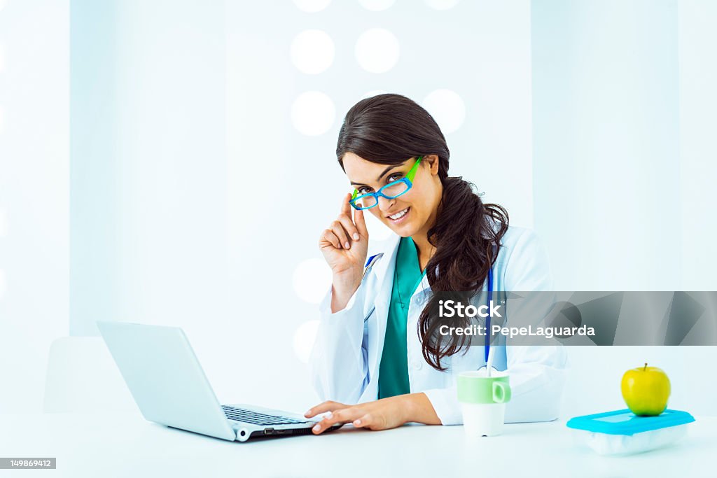 Cheerful doctor working in a white office Cheerful doctor working in a white office, with lunch box beside. Accidents and Disasters Stock Photo