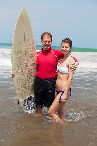 istock man with surf and  girl go on an ocean coast 149869421