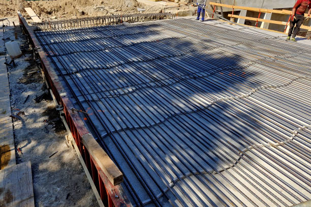 nessuna costruzione in cemento armato potrebbe fare a meno dell'acciaio di rinforzo. una piastra di ponte con un sacco di aste e montanti. versare nel calcestruzzo usando un camion di miscelazione. prodotto siderurgico - level rod foto e immagini stock