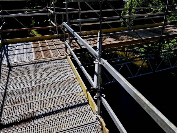 istock scascaffolding surrounds the bridge, serving as a temporaryffolding surrounds the bridge, serving as a temporary footbridge. the bridge over the water from below must be repaired by masons from the platform. he quickly stands up and folds himself onto car 1498696225