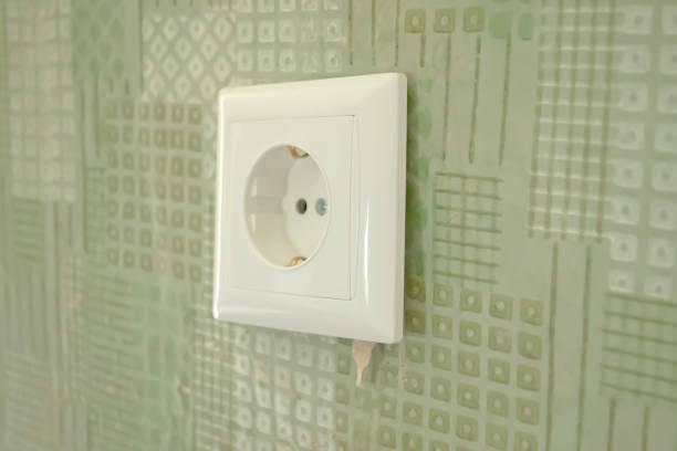 istock A white socket on the old wall. the gap between the socket and the wall. The socket almost fell out of the wall. Improper installation of the socket. 1498698146