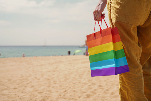 a bag in the colors of the rainbow on the beach. Gay pride on summer vacation