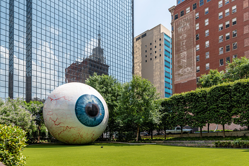 Dallas, Texas, USA. 2 June 2023. Large eye in a park in central Dallas with city behind.
