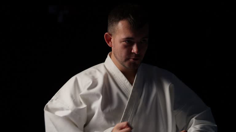 Taekwondo master doing solo training routine on black background, martial art