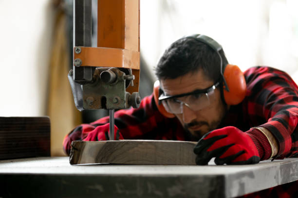 istock A young carpenter in a red checkered shirt and personal protective equipment processes wood in the workshop with a table band saw 1498702073