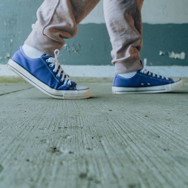 A male is strolling along a concrete sidewalk in a residential area