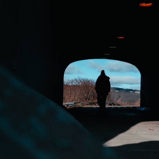istock a silhouette image of a man walking out of a dark tunnel 1498703295