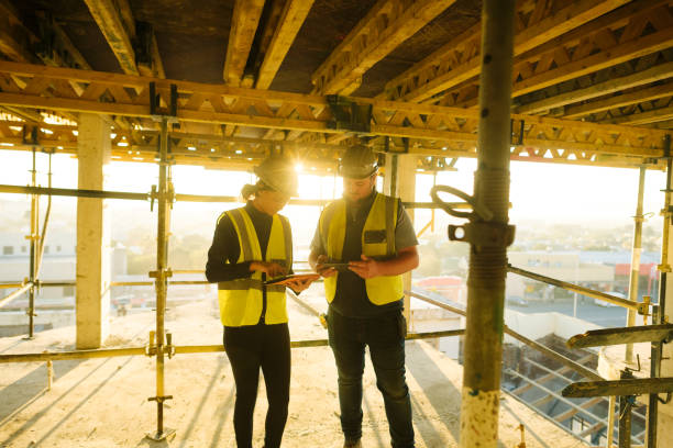 istock Sunrise Female and Male foreman and engineers with PPE on tablets on Construction Site at sunrise 1498703316