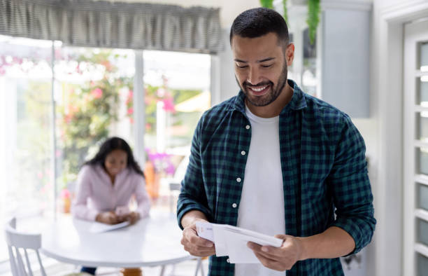 istock Happy man at home reading a letter he got in the mail 1498704776