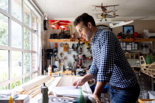 istock Man reading an instruction manual of an airplane model at his workshop 1498704814