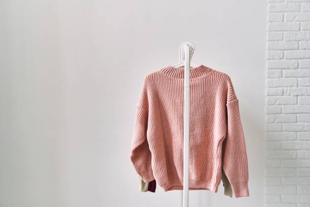 A woolen sweater hanging on a hanger on a white background. Warm clothes sale.