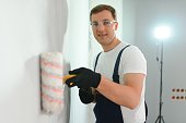 repair, building and home concept - close up of male in gloves holding painting roller