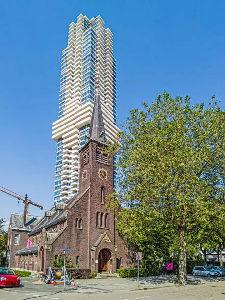 Photo of Shot of the historic Overdagkerk in Rotterdam in contrast to a modern apartment tower in the background