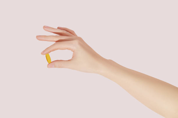 istock Hand holding the supplements (omega 3, vitamins) on pink background 1498716843