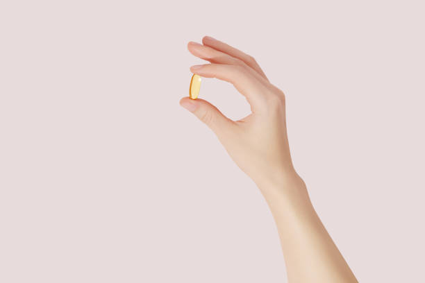 istock Hand holding the supplements (omega 3, vitamins) on pink background 1498716852