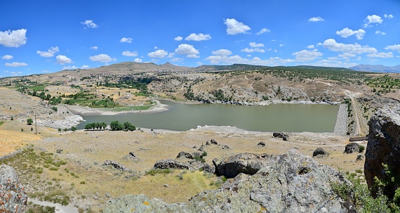 This image features a hill with rocky terrain and small ponds at its summit