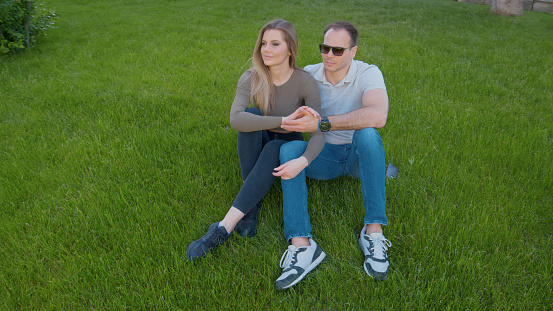 Relaxing on the lush green grass, the couple takes pleasure in the beauty of the natural environment