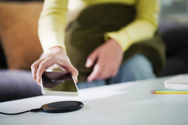 istock Charging mobile phone battery with wireless charging device in the table. Smartphone charging on a charging pad. Mobile phone near wireless charger Modern lifestyle technology concept. 1498720503