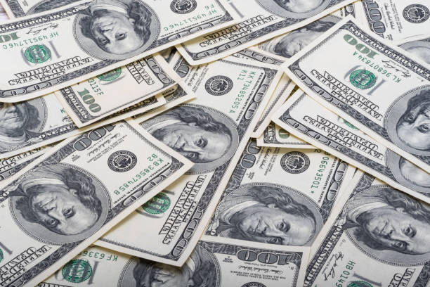 istock 100 dollar bills on wooden background 1498721143