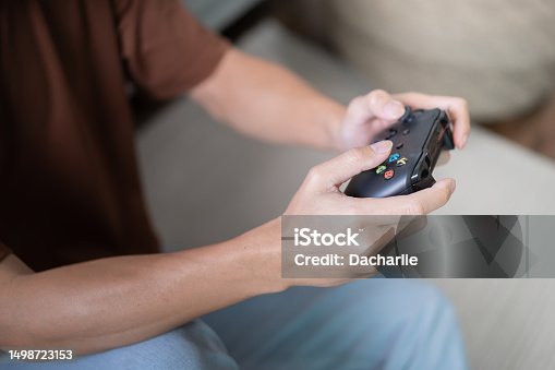 istock Young Asian man gamer controller video console playing holding hobby playful Online Video Game enjoyment eSport Cyber Games Internet. 1498723153