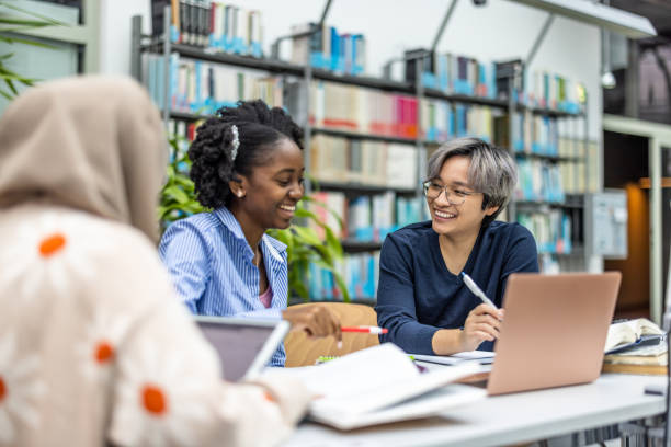 istock Multiethnic group of students sitting in a library and studying together 1498725438
