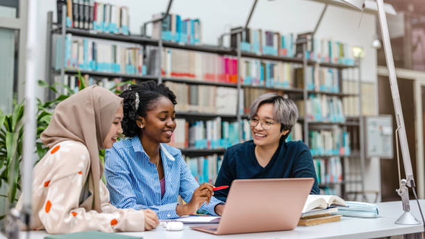istock Multiethnic group of students sitting in a library and studying together 1498725443