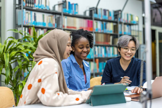 istock Multiethnic group of students sitting in a library and studying together 1498725445