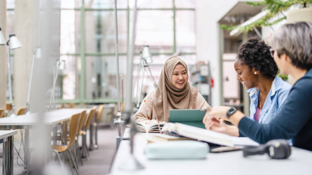 istock Multiethnic group of students sitting in a library and studying together 1498725633